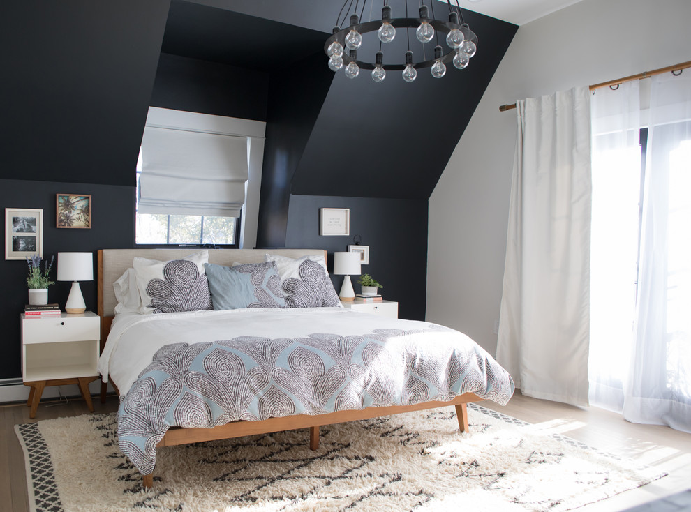 Transitional bedroom in New York with black walls, light hardwood floors and no fireplace.