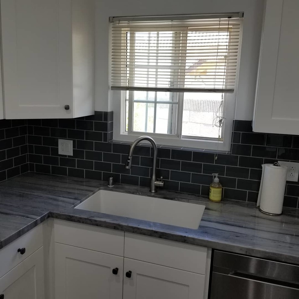 Small transitional u-shaped eat-in kitchen with an undermount sink, shaker cabinets, white cabinets, soapstone benchtops, black splashback, subway tile splashback, stainless steel appliances, no island, grey floor and grey benchtop.