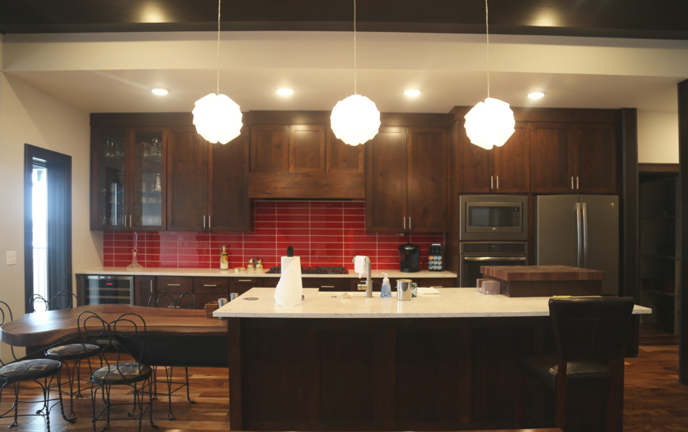 Large transitional single-wall medium tone wood floor eat-in kitchen photo with an undermount sink, recessed-panel cabinets, dark wood cabinets, granite countertops, red backsplash, ceramic backsplash, stainless steel appliances and an island