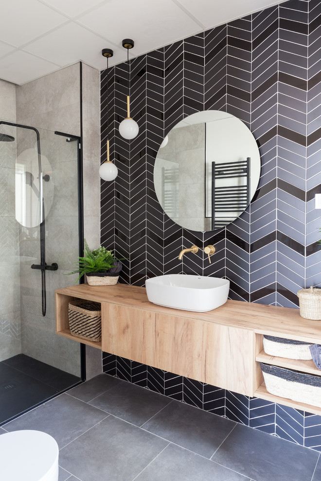 This is an example of a large scandinavian master bathroom in Madrid with furniture-like cabinets, white cabinets, a curbless shower, a one-piece toilet, black and white tile, ceramic tile, grey walls, ceramic floors, a vessel sink, wood benchtops, black floor, a shower curtain and brown benchtops.