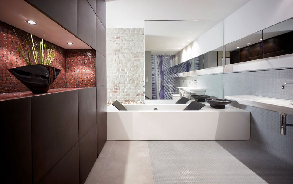 Badezimmer With flächenbündigen Schrankfronten, schwarzen Schränken, Einbaubadewanne, grauen Fliesen, Mosaikfliesen, weißer Wandfarbe, Mosaik-Bodenfliesen and integriertem Waschbecken in Leipzig