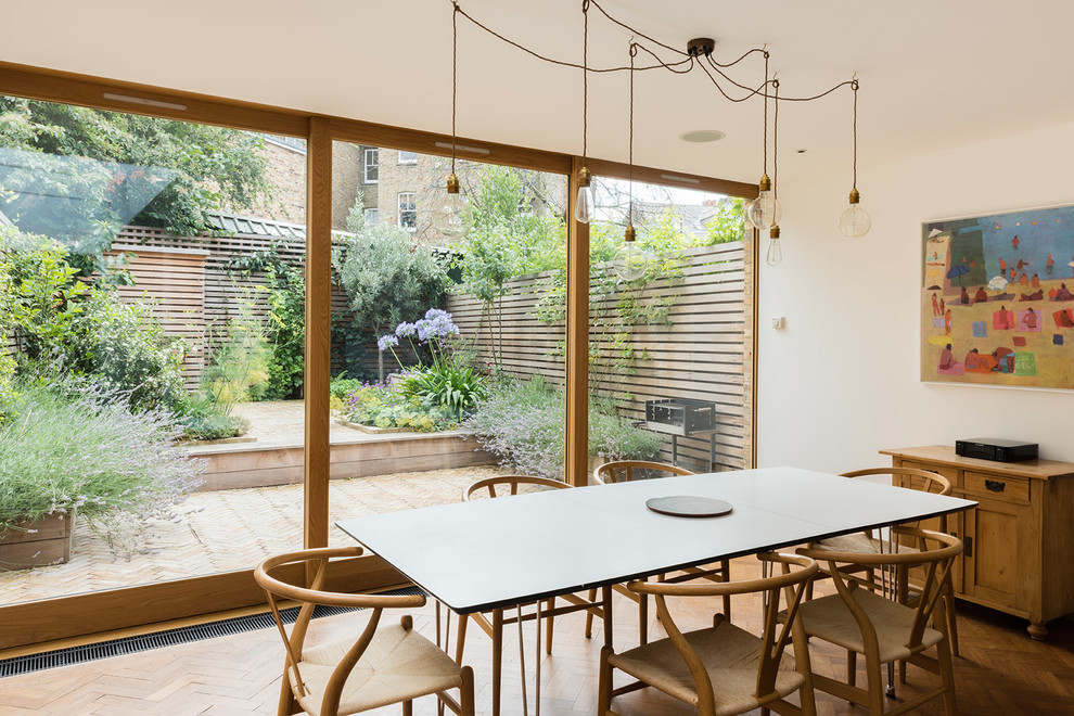 Contemporary kitchen/dining combo in London with white walls, medium hardwood floors and brown floor.