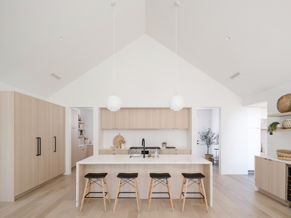 Design ideas for a scandinavian open plan kitchen in Phoenix with a single-bowl sink, flat-panel cabinets, light wood cabinets, quartz benchtops, white splashback, porcelain splashback, panelled appliances, light hardwood floors, with island, white benchtop and vaulted.