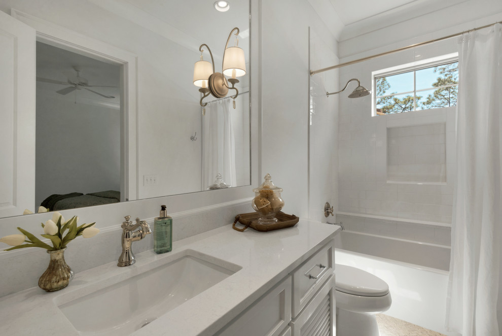 This is an example of a large beach style kids bathroom in Other with louvered cabinets, white cabinets, an alcove tub, a shower/bathtub combo, a one-piece toilet, white walls and an undermount sink.