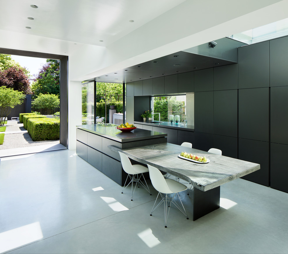 Large contemporary galley kitchen in London with an undermount sink, flat-panel cabinets, black cabinets, with island, grey floor and black benchtop.