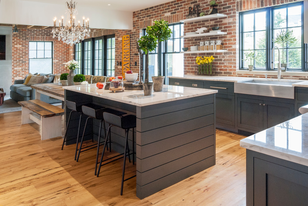 Design ideas for a mid-sized country eat-in kitchen in Cleveland with a farmhouse sink, shaker cabinets, blue cabinets, marble benchtops, multi-coloured splashback, stainless steel appliances, light hardwood floors and with island.