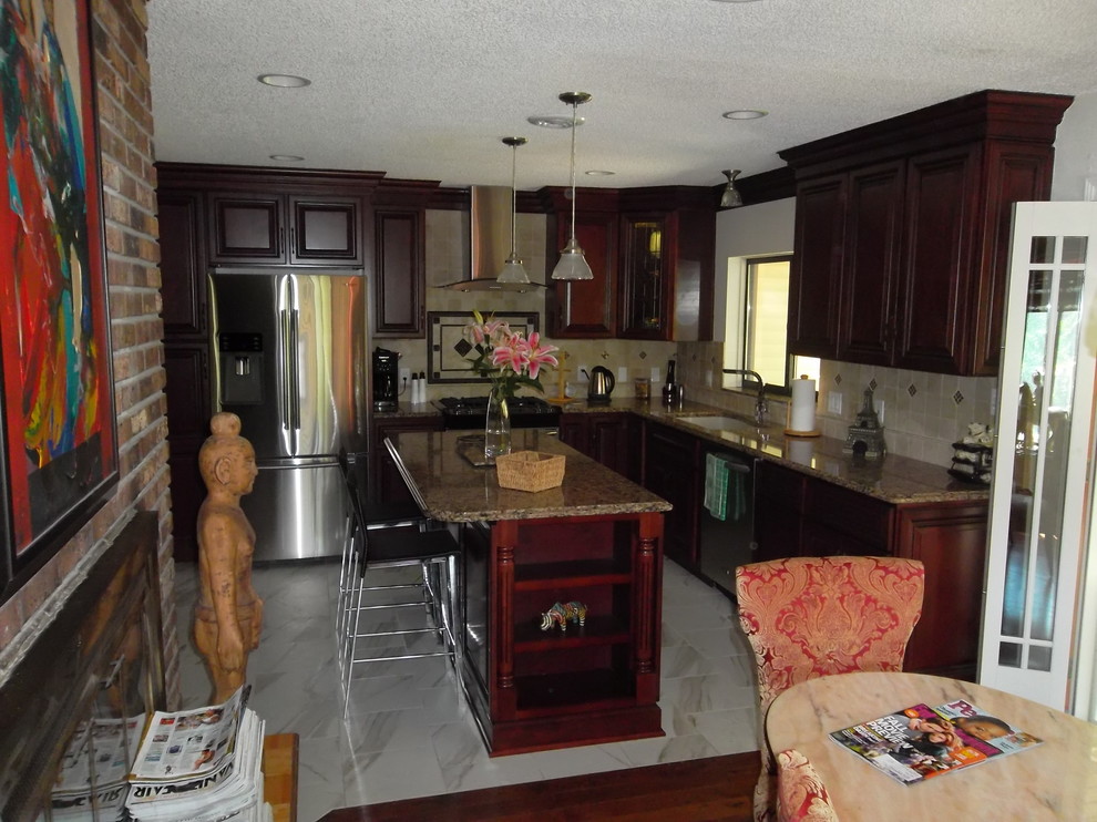 Kitchen - mid-sized transitional l-shaped ceramic tile kitchen idea with a drop-in sink, dark wood cabinets, granite countertops, stone tile backsplash, stainless steel appliances, an island and raised-panel cabinets