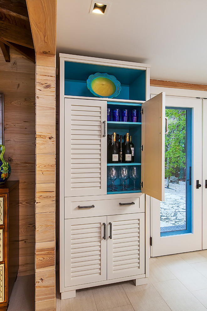 Photo of a small beach style single-wall home bar in Detroit with no sink, louvered cabinets, beige cabinets and beige floor.