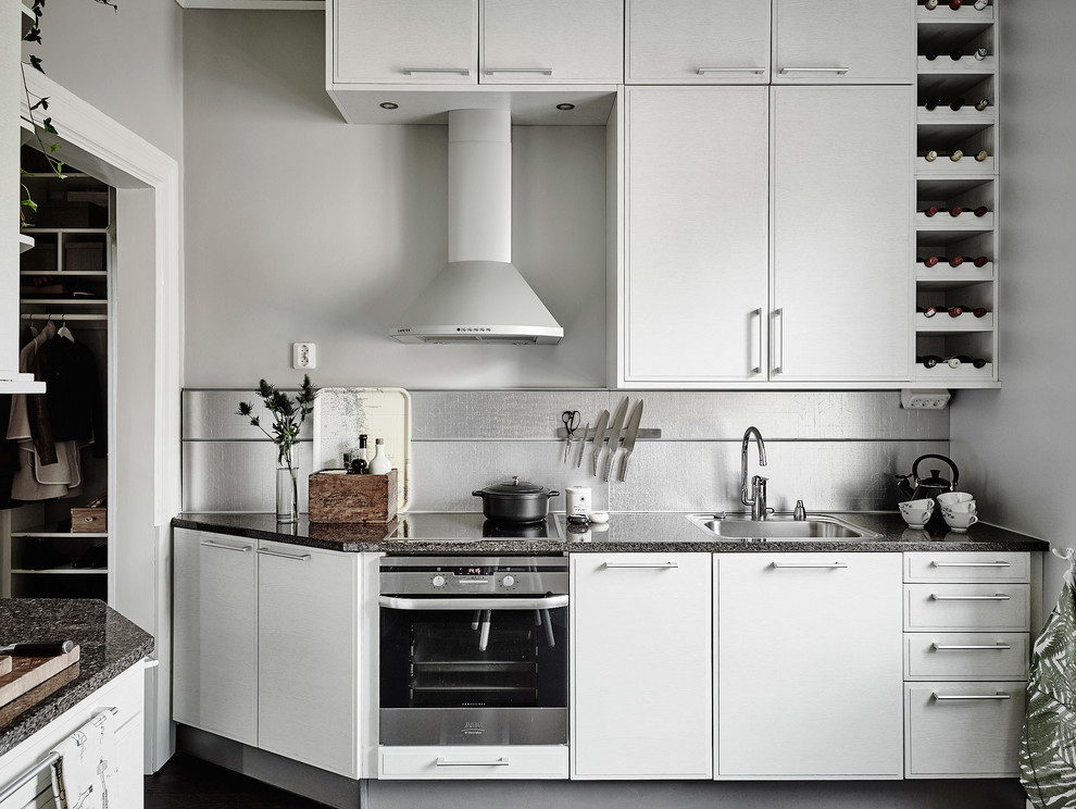 Photo of a large scandinavian single-wall kitchen in Gothenburg with a single-bowl sink, flat-panel cabinets, white cabinets, granite benchtops, white appliances and no island.