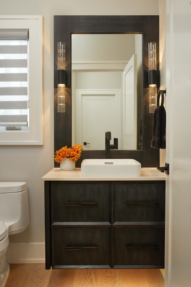 Design ideas for a mid-sized transitional 3/4 bathroom in Grand Rapids with black cabinets, beige walls, light hardwood floors, a vessel sink, brown floor, recessed-panel cabinets, a one-piece toilet, onyx benchtops and beige benchtops.