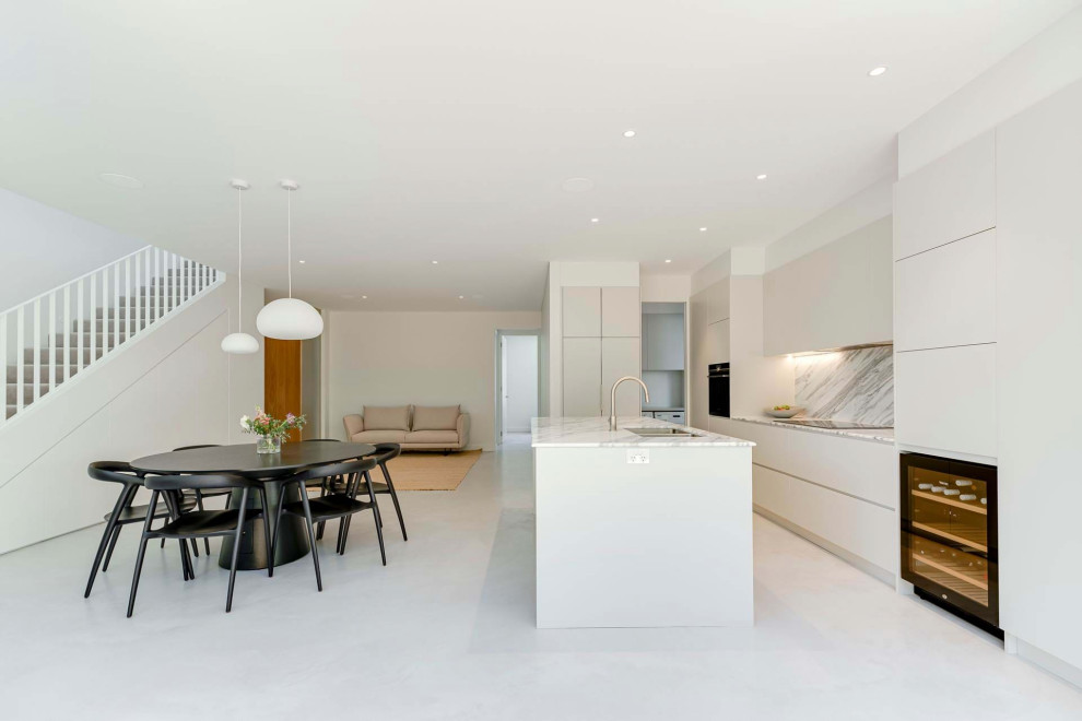 Photo of a large modern l-shaped eat-in kitchen in Sydney with a double-bowl sink, flat-panel cabinets, beige cabinets, marble benchtops, multi-coloured splashback, marble splashback, stainless steel appliances, ceramic floors, with island, beige floor and white benchtop.