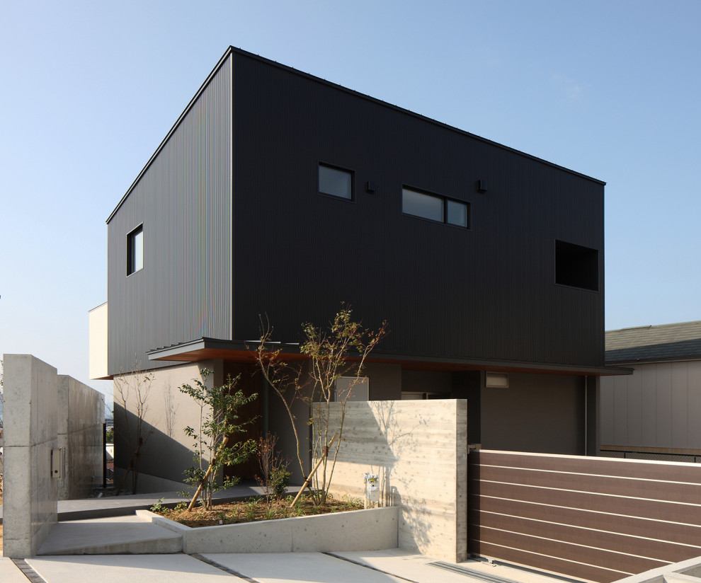 Aménagement d'une grande façade de maison noire moderne en béton et planches et couvre-joints à un étage avec un toit en appentis, un toit en métal et un toit noir.