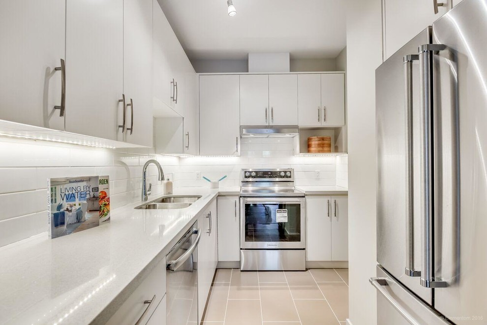 Enclosed kitchen - small contemporary l-shaped porcelain tile and beige floor enclosed kitchen idea with an undermount sink, flat-panel cabinets, white cabinets, white backsplash, ceramic backsplash, stainless steel appliances, no island and white countertops