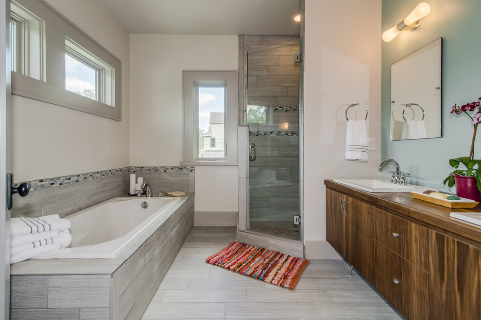 Inspiration for a mid-sized contemporary master bathroom in Nashville with a drop-in sink, furniture-like cabinets, dark wood cabinets, wood benchtops, a drop-in tub, a corner shower, a two-piece toilet, gray tile, porcelain tile, blue walls and porcelain floors.