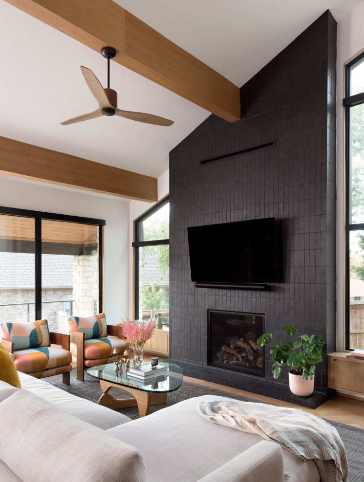 Design ideas for a transitional open concept living room in Austin with light hardwood floors, a standard fireplace, a tile fireplace surround, a wall-mounted tv and exposed beam.