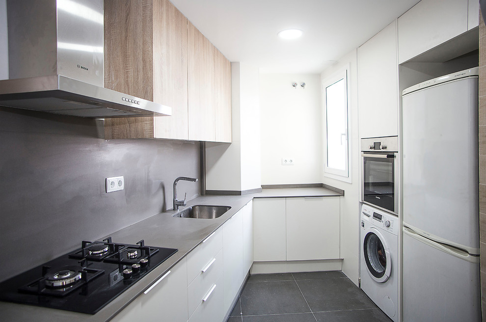 Photo of a mid-sized contemporary u-shaped separate kitchen in Barcelona with a single-bowl sink, white cabinets, grey splashback, white appliances, no island and grey floor.