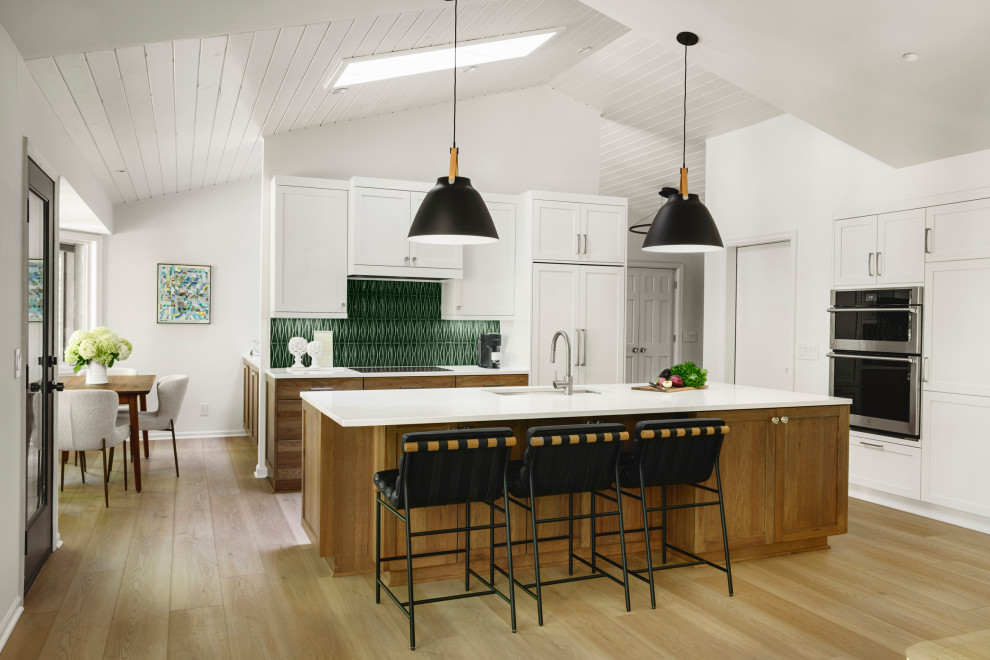 Inspiration för ett stort vintage vit vitt kök, med en undermonterad diskho, luckor med infälld panel, vita skåp, bänkskiva i kvarts, grönt stänkskydd, stänkskydd i keramik, rostfria vitvaror, mellanmörkt trägolv, en köksö och brunt golv