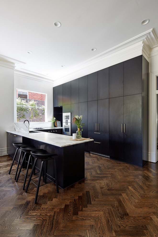Design ideas for a mid-sized traditional u-shaped eat-in kitchen in Melbourne with a double-bowl sink, black cabinets, marble benchtops, multi-coloured splashback, marble splashback, stainless steel appliances, medium hardwood floors, with island, brown floor and multi-coloured benchtop.