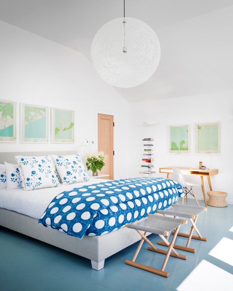 Photo of a large beach style master bedroom in New York with white walls, painted wood floors, no fireplace and blue floor.