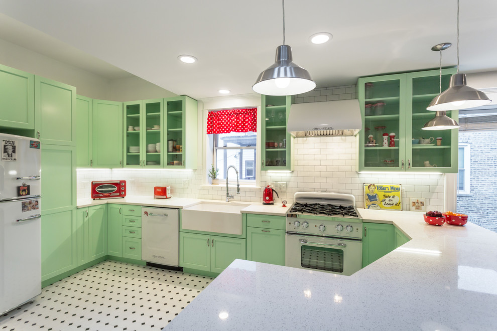 This is an example of a mid-sized traditional l-shaped open plan kitchen in Chicago with a farmhouse sink, green cabinets, white splashback, subway tile splashback, white appliances, a peninsula, quartz benchtops and porcelain floors.