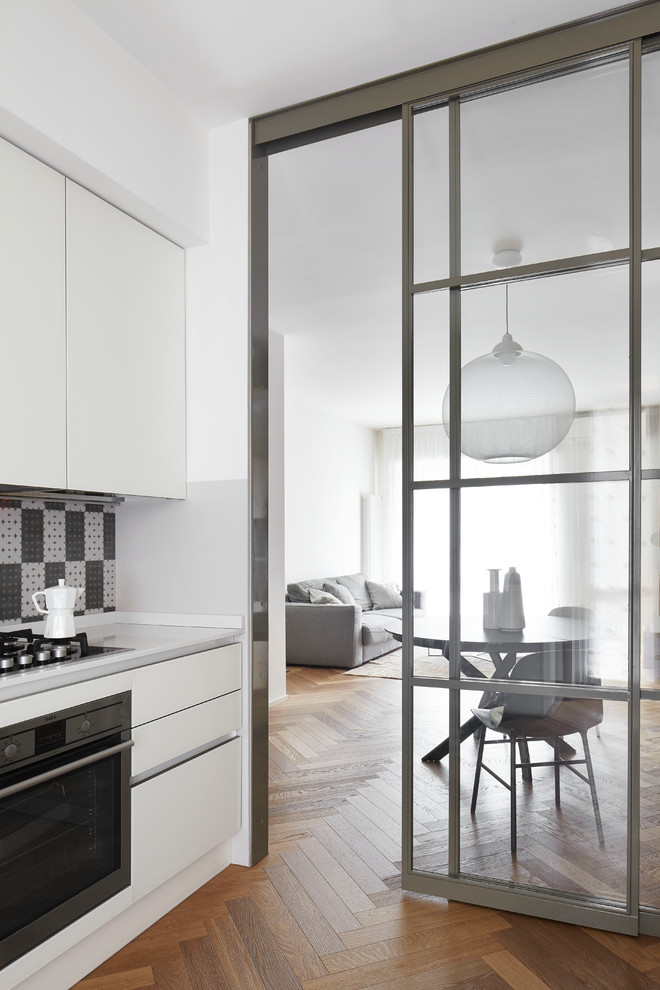 Contemporary kitchen in Milan with flat-panel cabinets, white cabinets, multi-coloured splashback, stainless steel appliances and medium hardwood floors.