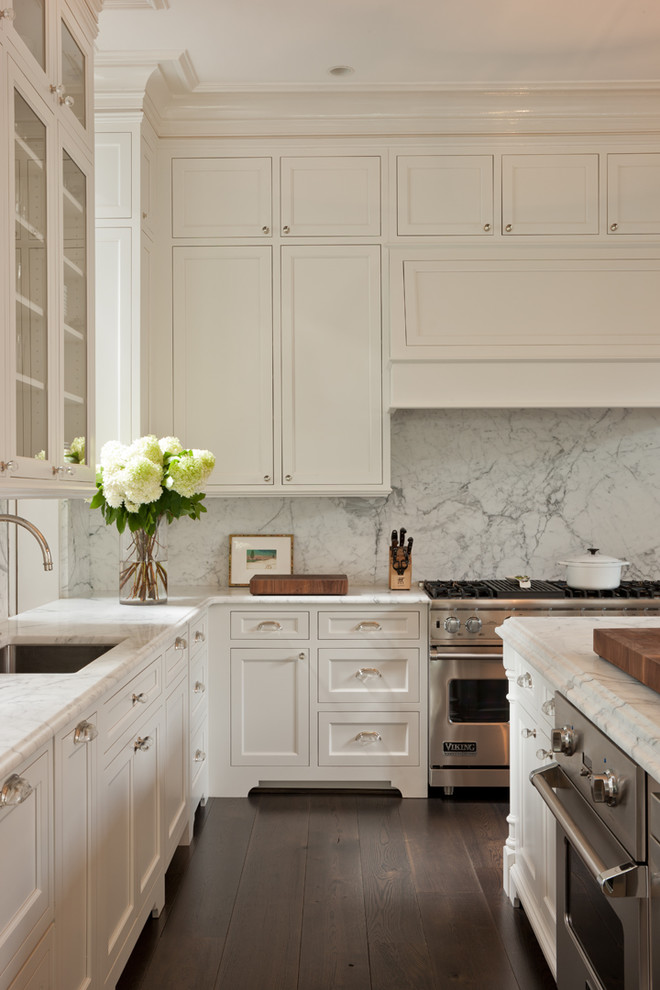 Transitional kitchen in DC Metro with an undermount sink, recessed-panel cabinets, white cabinets, marble benchtops, white splashback, stone slab splashback, panelled appliances, dark hardwood floors and with island.