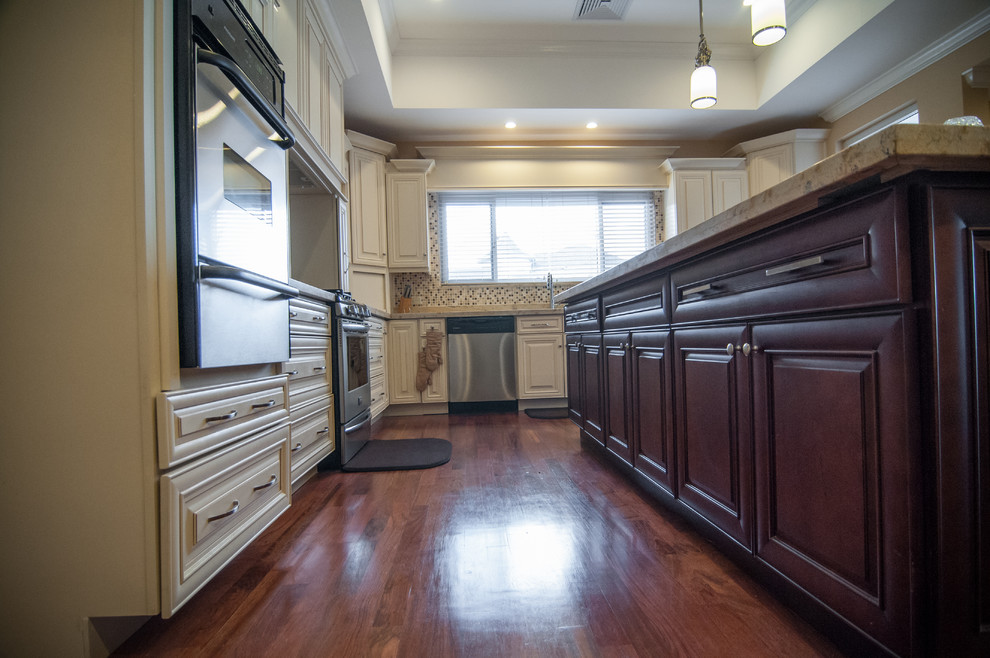 Large traditional l-shaped open plan kitchen in Miami with an undermount sink, raised-panel cabinets, white cabinets, granite benchtops, mosaic tile splashback, stainless steel appliances and medium hardwood floors.