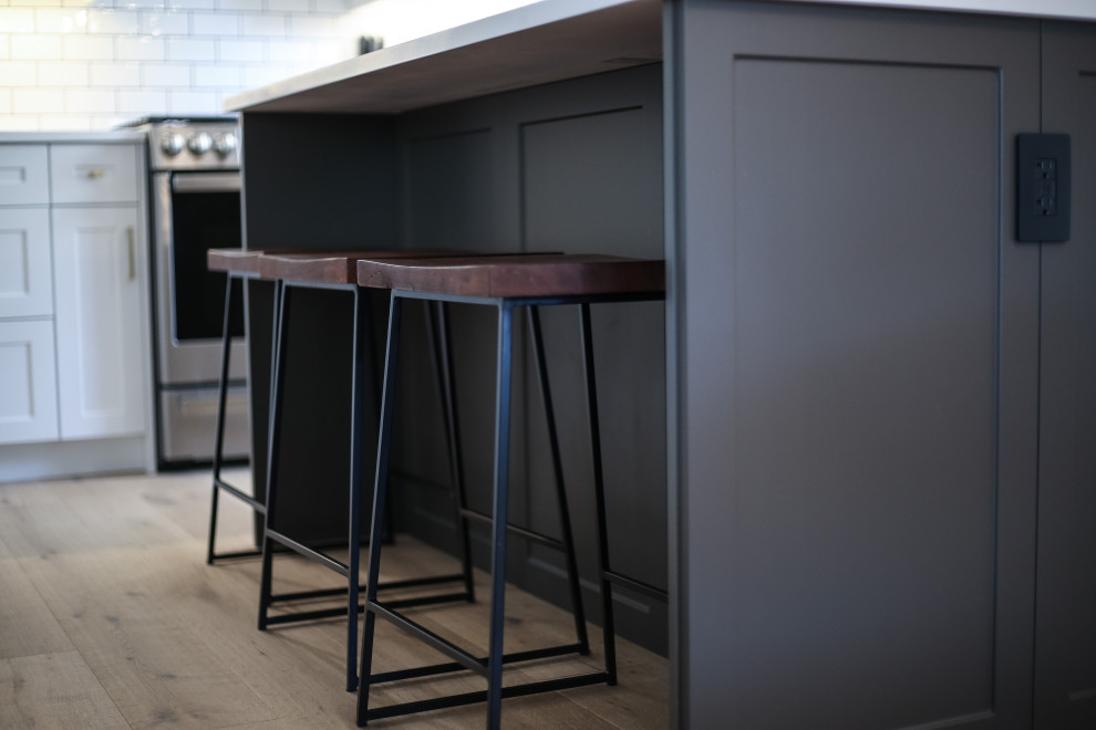 Inspiration for a small l-shaped light wood floor eat-in kitchen remodel with a farmhouse sink, shaker cabinets, quartz countertops, white backsplash, porcelain backsplash, stainless steel appliances, an island and white countertops