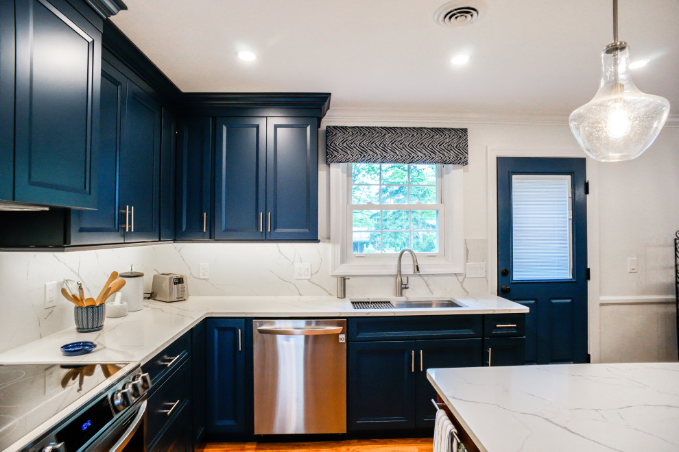 Inredning av ett klassiskt vit vitt kök och matrum, med luckor med infälld panel, blå skåp, bänkskiva i kvarts, vitt stänkskydd, mellanmörkt trägolv, en köksö och brunt golv