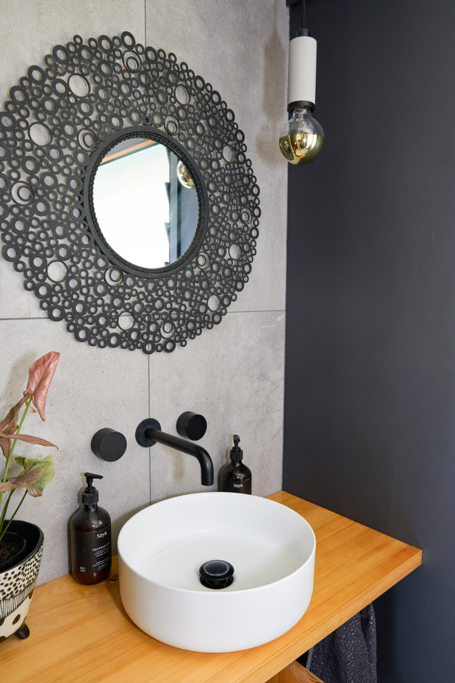 Cette photo montre un petit WC et toilettes montagne en bois clair avec WC à poser, un carrelage gris, des carreaux de céramique, un mur gris, un sol en carrelage de céramique, une vasque, un sol gris et meuble-lavabo encastré.