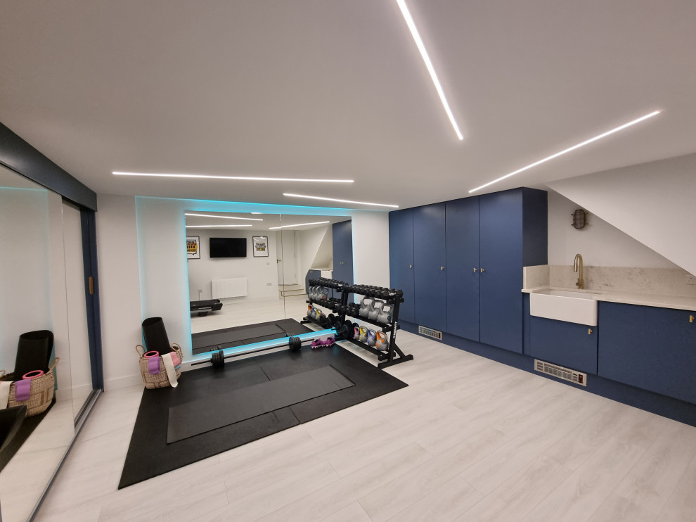 This is an example of a mid-sized contemporary multipurpose gym in London with white walls, laminate floors, multi-coloured floor and recessed.