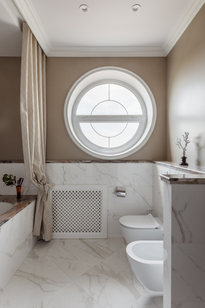 Пример оригинального дизайна: большая главная, серо-белая ванная комната в стиле неоклассика (современная классика) с ванной в нише, душем в нише, биде, белой плиткой, серыми стенами, врезной раковиной, мраморной столешницей, душем с раздвижными дверями, сиденьем для душа, тумбой под две раковины и напольной тумбой