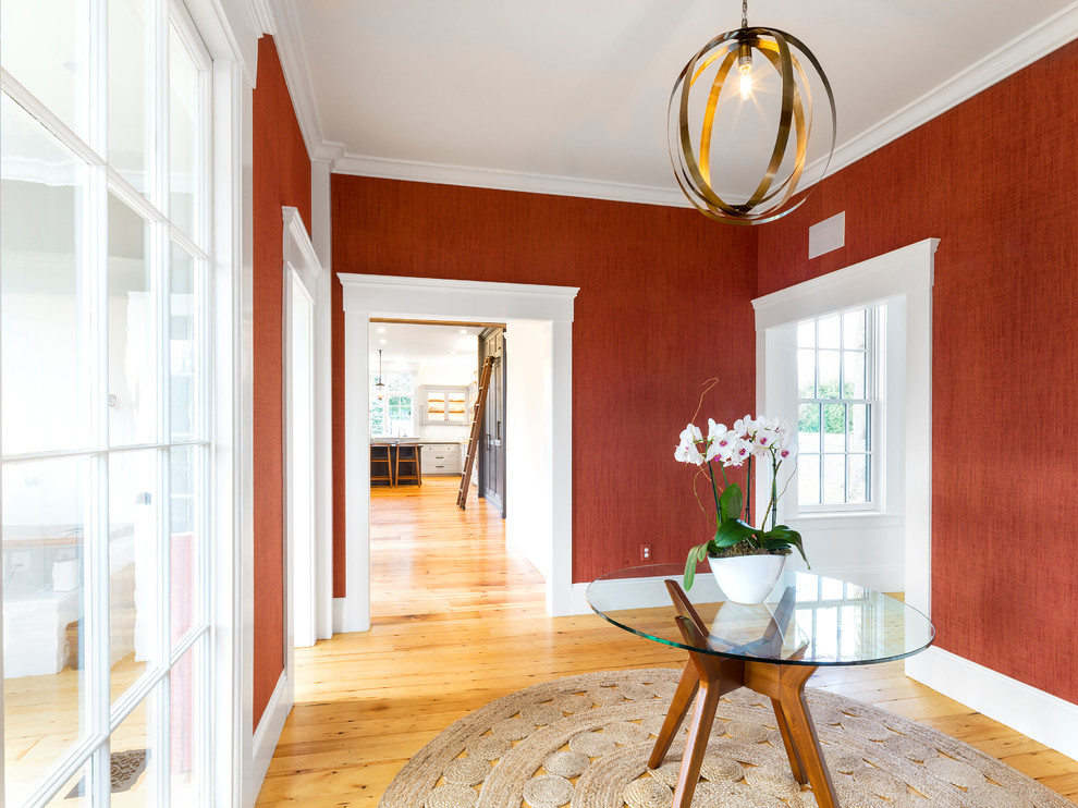 This is an example of a large transitional foyer in Boston with red walls, light hardwood floors, a single front door and a medium wood front door.