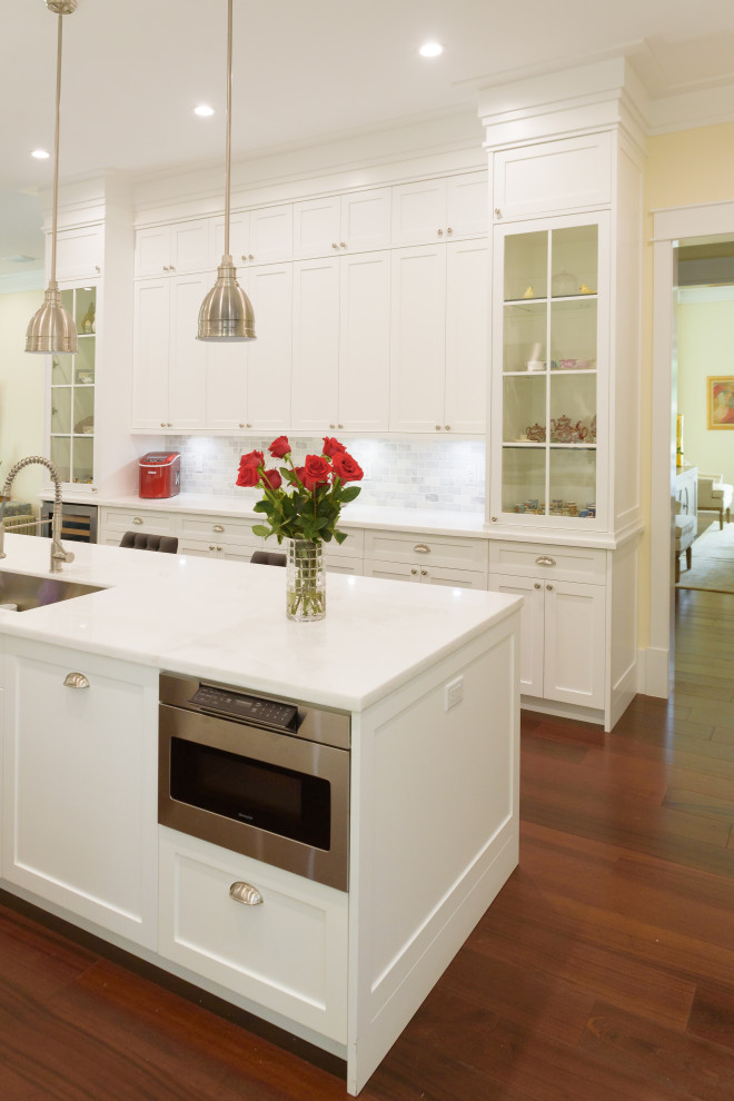 Inspiration for a large country galley open plan kitchen in Miami with an undermount sink, shaker cabinets, white cabinets, quartz benchtops, grey splashback, porcelain splashback, stainless steel appliances, medium hardwood floors, with island, brown floor and white benchtop.