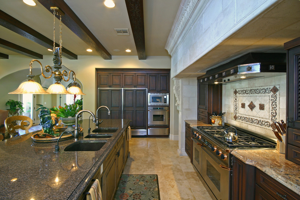 Photo of an expansive traditional galley eat-in kitchen in Louisville with an undermount sink, raised-panel cabinets, dark wood cabinets, granite benchtops, black splashback, stone tile splashback, panelled appliances, travertine floors and with island.