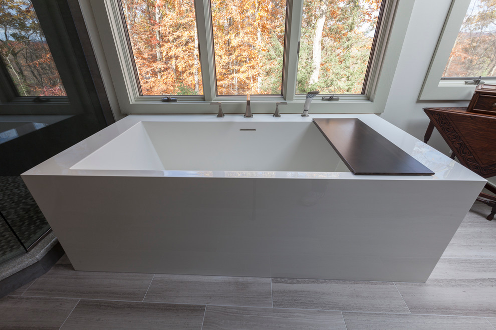 This is an example of a large modern master bathroom in New York with flat-panel cabinets, brown cabinets, a freestanding tub, a corner shower, a two-piece toilet, gray tile, porcelain tile, grey walls, travertine floors, an undermount sink, recycled glass benchtops, grey floor and a hinged shower door.