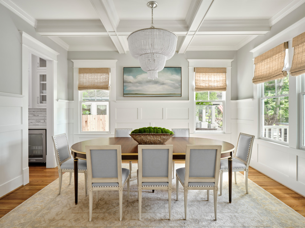 This is an example of a medium sized beach style enclosed dining room in Houston with grey walls, medium hardwood flooring, a standard fireplace, a stone fireplace surround, brown floors, a coffered ceiling and wainscoting.