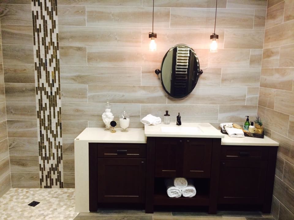 Photo of a country bathroom in Orlando with recessed-panel cabinets, dark wood cabinets, a curbless shower, gray tile, porcelain tile, pebble tile floors, an undermount sink and engineered quartz benchtops.