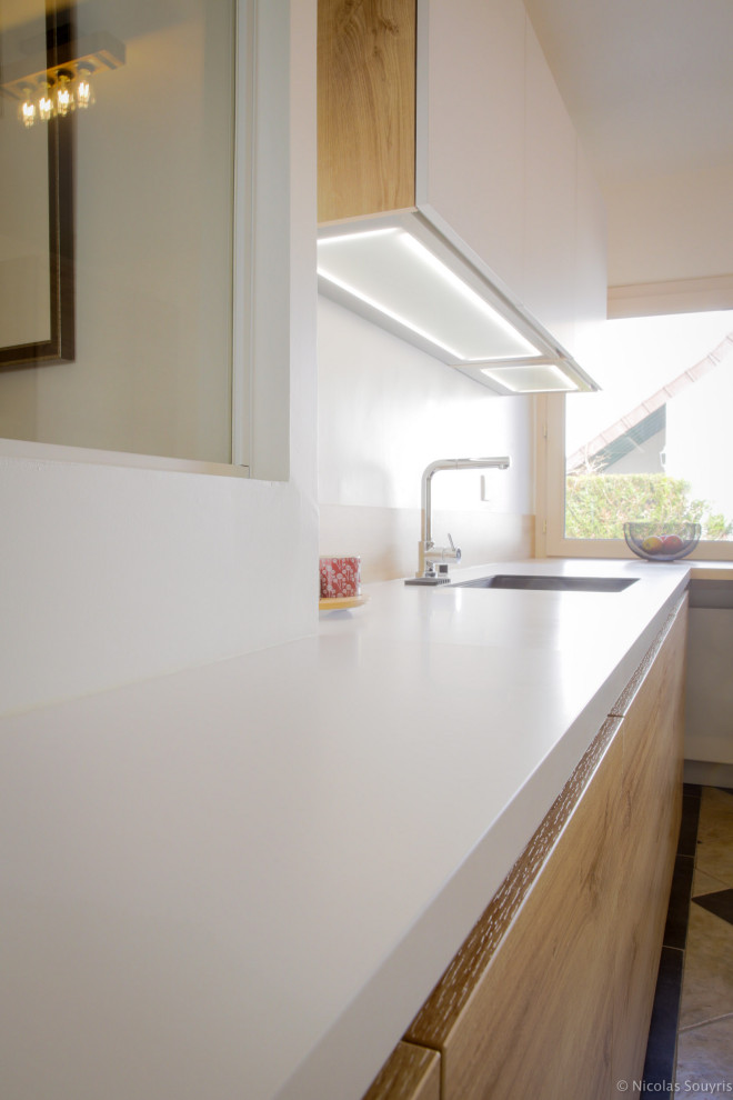 Inredning av ett industriellt mellanstort vit vitt kök, med en integrerad diskho, luckor med profilerade fronter, vita skåp, bänkskiva i koppar, vitt stänkskydd, svarta vitvaror, klinkergolv i keramik och beiget golv