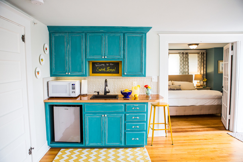 Design ideas for a small traditional single-wall open plan kitchen in Austin with a single-bowl sink, recessed-panel cabinets, turquoise cabinets, wood benchtops, grey splashback, metal splashback and medium hardwood floors.
