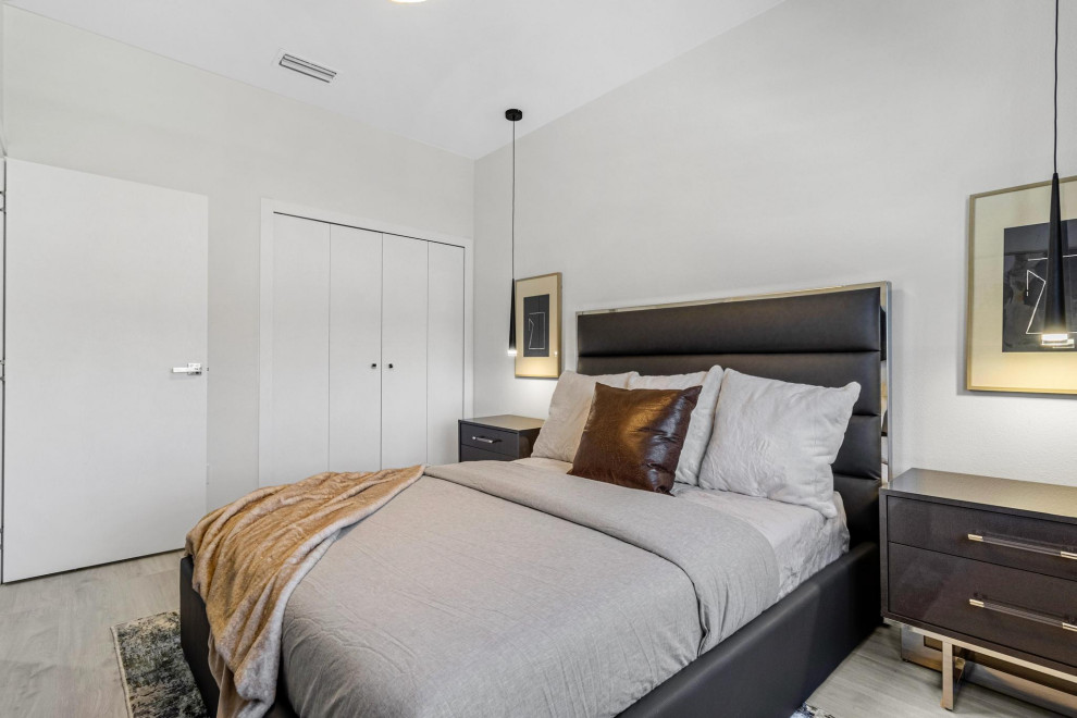 Photo of a large contemporary master bedroom in Tampa with white walls, light hardwood flooring and beige floors.