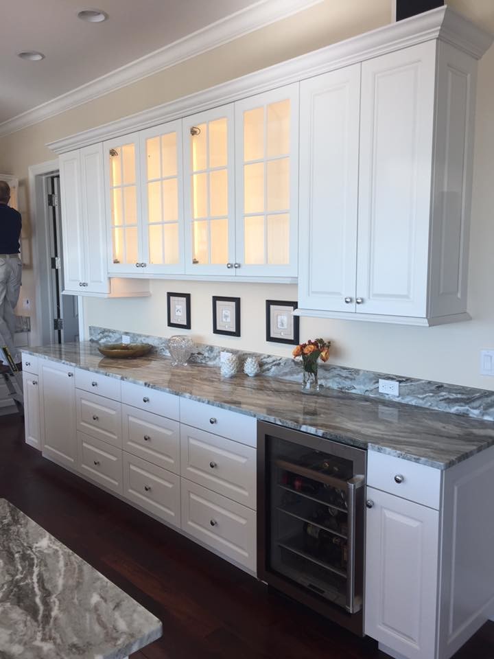Example of a mid-sized transitional l-shaped dark wood floor and brown floor open concept kitchen design with an undermount sink, raised-panel cabinets, white cabinets, granite countertops, stainless steel appliances and an island