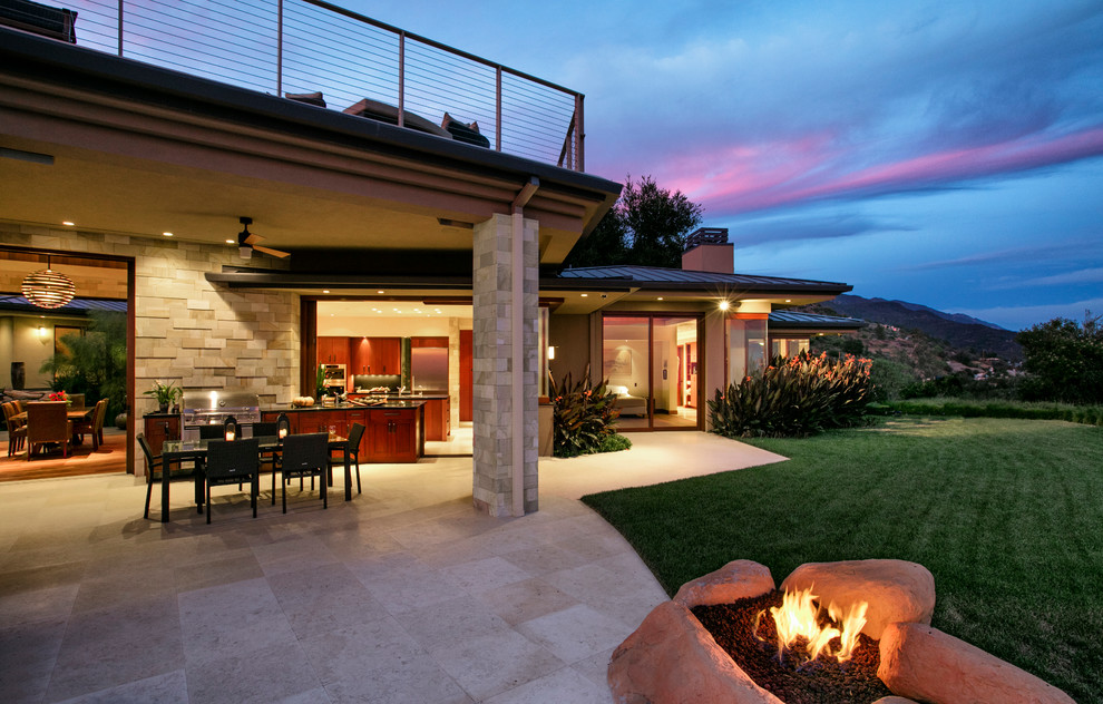 Inspiration for an expansive tropical backyard patio in Santa Barbara with a fire feature and a roof extension.