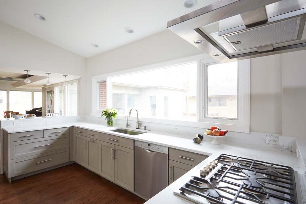 Example of a large transitional u-shaped medium tone wood floor and brown floor eat-in kitchen design in Chicago with a single-bowl sink, shaker cabinets, gray cabinets, quartz countertops, white backsplash, ceramic backsplash, stainless steel appliances and a peninsula