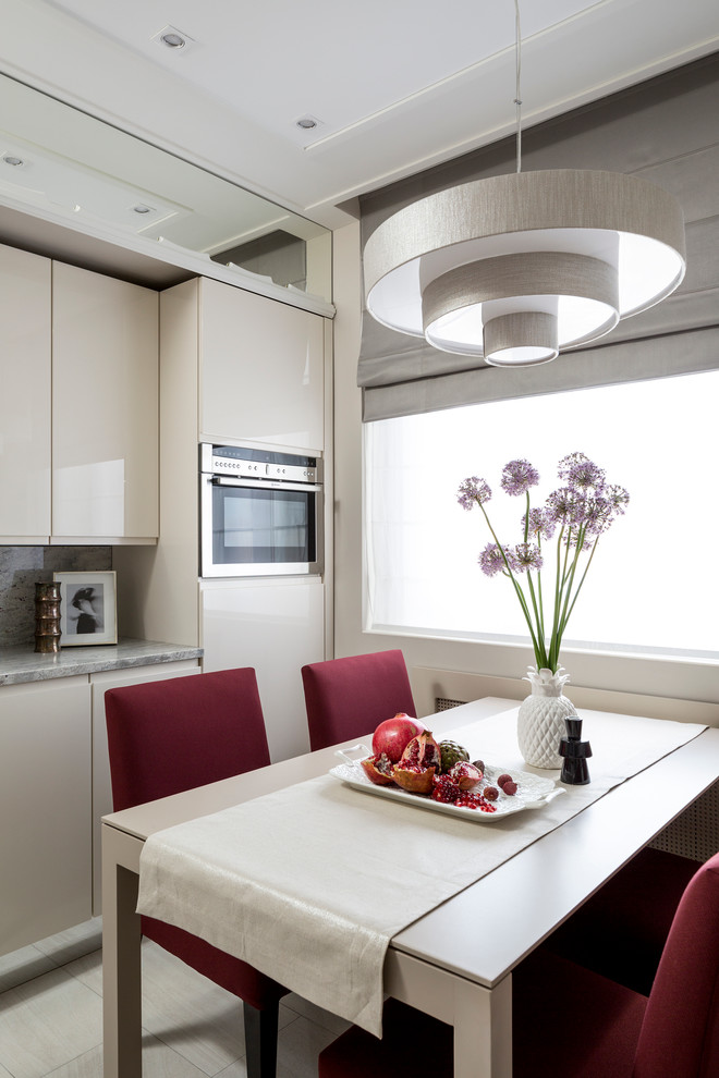 This is an example of a contemporary kitchen in Moscow with flat-panel cabinets, beige cabinets, grey splashback and stainless steel appliances.