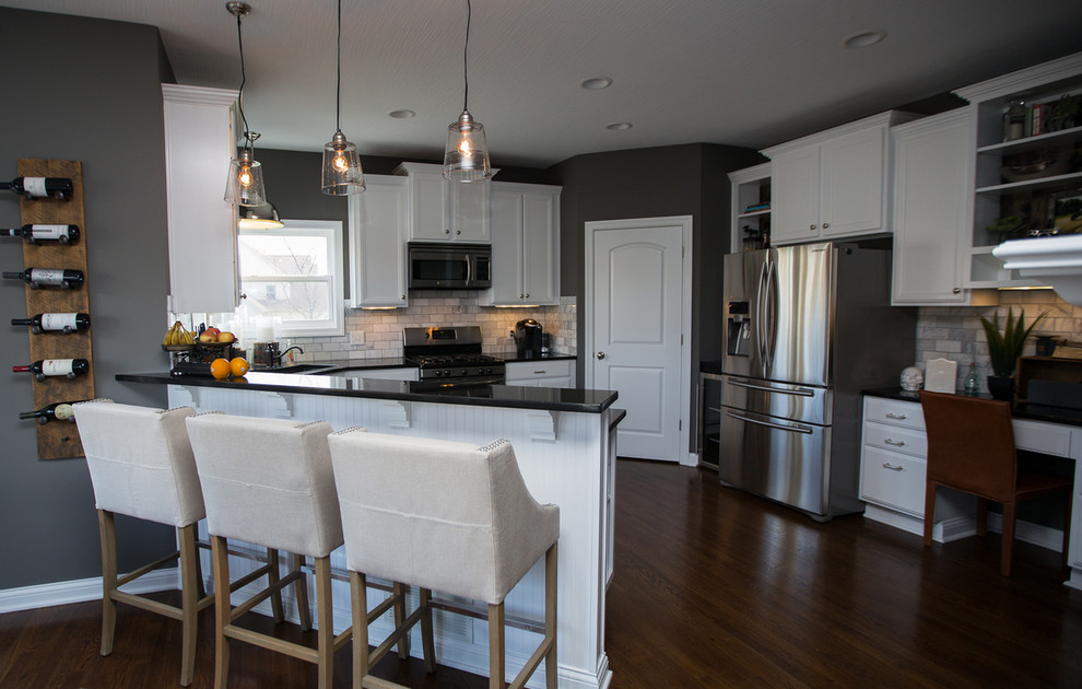 Eat-in kitchen - mid-sized transitional l-shaped medium tone wood floor eat-in kitchen idea in Columbus with an undermount sink, recessed-panel cabinets, white cabinets, solid surface countertops, gray backsplash, ceramic backsplash, stainless steel appliances and an island