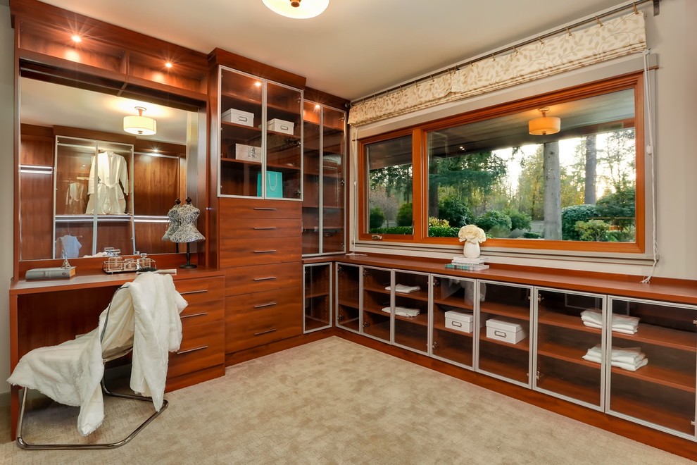 Contemporary women's dressing room in Seattle with glass-front cabinets, medium wood cabinets, carpet and beige floor.