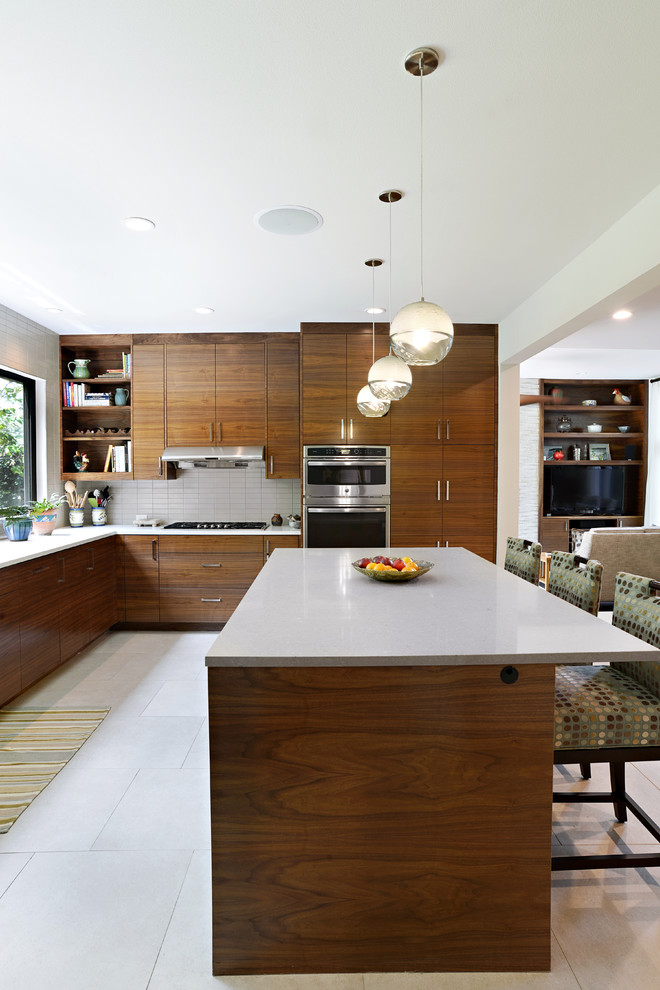 This is an example of a large midcentury u-shaped eat-in kitchen in Dallas with a drop-in sink, flat-panel cabinets, medium wood cabinets, quartz benchtops, white splashback, subway tile splashback, stainless steel appliances, porcelain floors, with island and white floor.