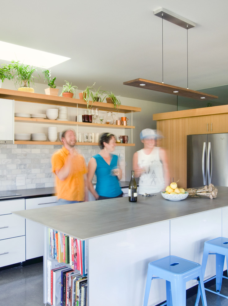 This is an example of a mid-sized contemporary u-shaped open plan kitchen in Seattle with open cabinets, light wood cabinets, white splashback, stainless steel appliances, concrete floors, with island and grey floor.