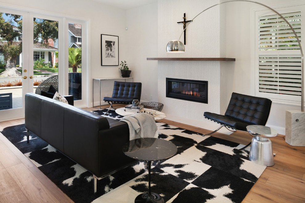 This is an example of a mid-sized contemporary open concept family room in Orange County with white walls, medium hardwood floors, a tile fireplace surround, no tv, brown floor and a ribbon fireplace.